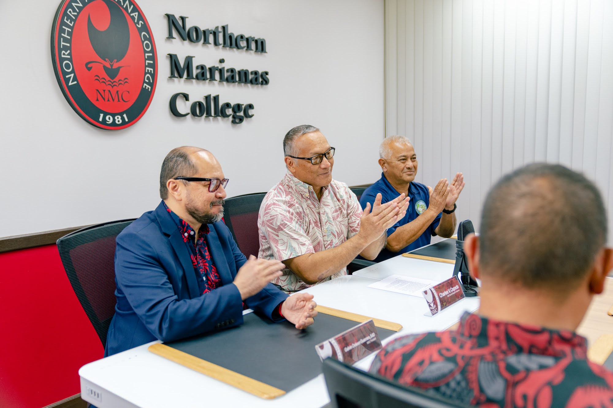 Northern Marianas College President Dr. Galvin S. Deleon Guerrero, left, shakes hands with NMC Board of Regents Chairman Charles V. Cepeda, center, as NMC Foundation Chairman Vicente Babauta, third right, and other members of the Board of Regents applaud in the NMC Board of Regents conference room on Thursday.